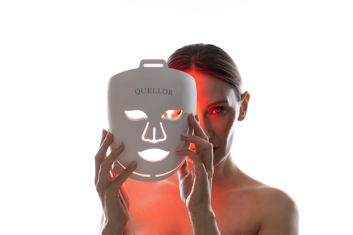 Woman holding an illuminated Quellor LED light therapy mask