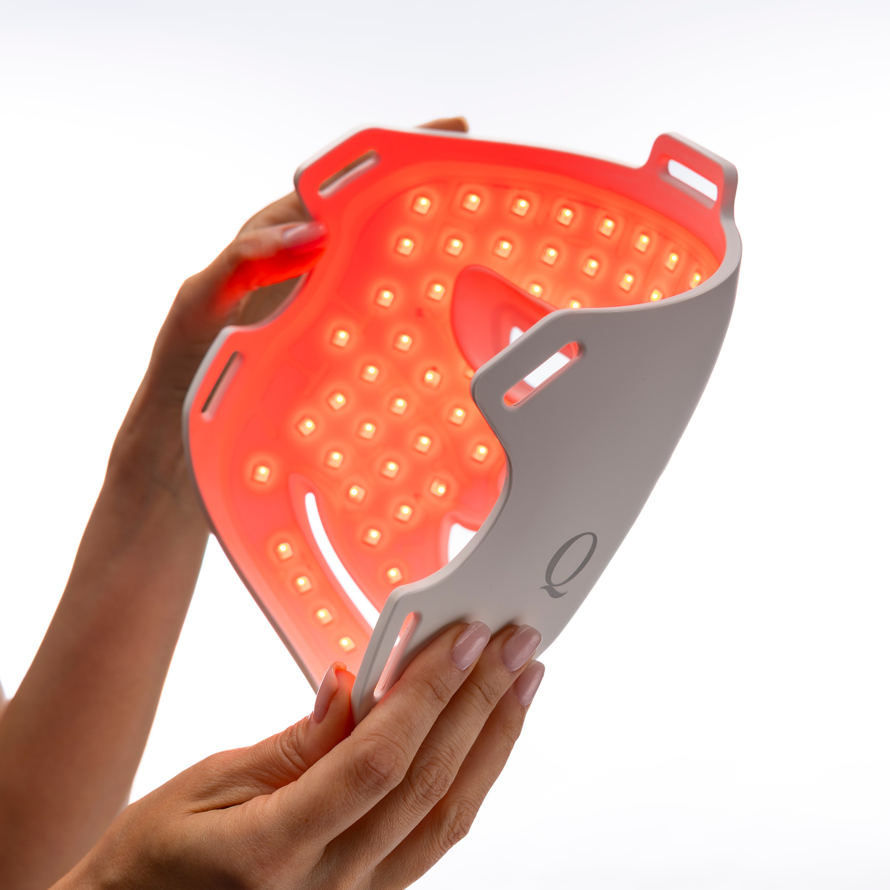 Close-up of the illuminated Quellor LED Light Therapy Mask held in hand.